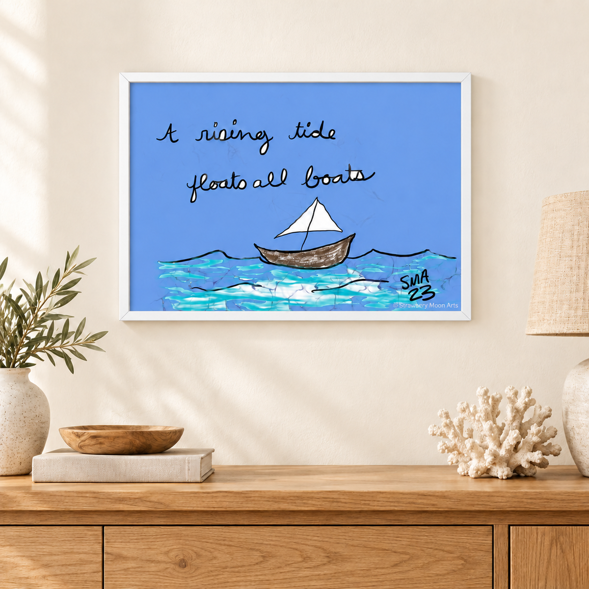A Rising Tide by Stephanie Anderson, white-framed artwork in a coastal room, with Strawberry Moon Arts watermark.