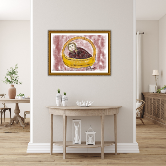 A framed art print featuring a whimsical illustration of a cat in a yellow basket on a pinkish-purple background, displayed on a light beige wall above a wooden console table in a styled home interior.
